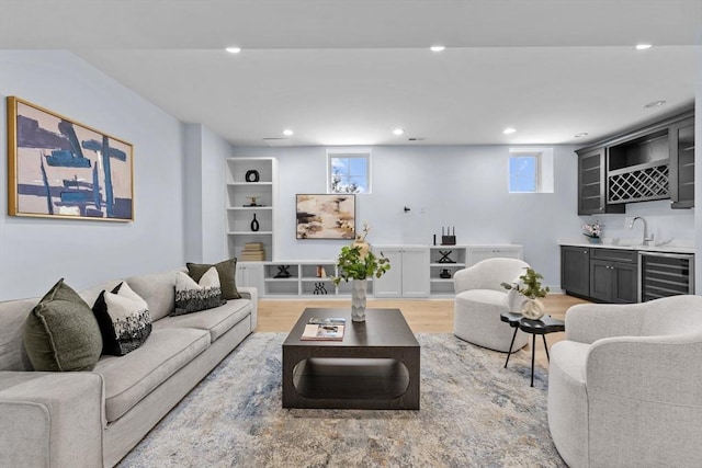 living area with light wood finished floors, beverage cooler, wet bar, and recessed lighting