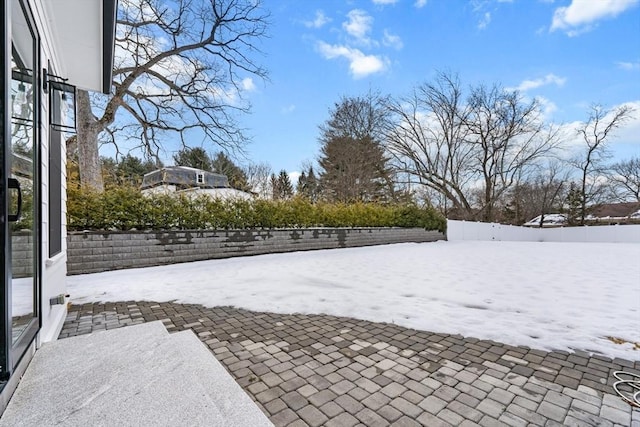 yard layered in snow featuring a patio area and fence