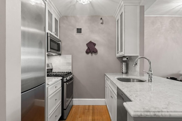 42 8th St Unit 4106, Boston, MA 02129 - kitchen with stainless steel appliances, a sink, decorative backsplash, a peninsula, and light wood-style floors