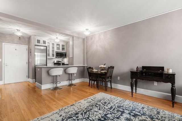 42 8th St Unit 4106, Boston, MA 02129 - kitchen featuring appliances with stainless steel finishes, light wood-style flooring, white cabinetry, a breakfast bar, and glass insert cabinets