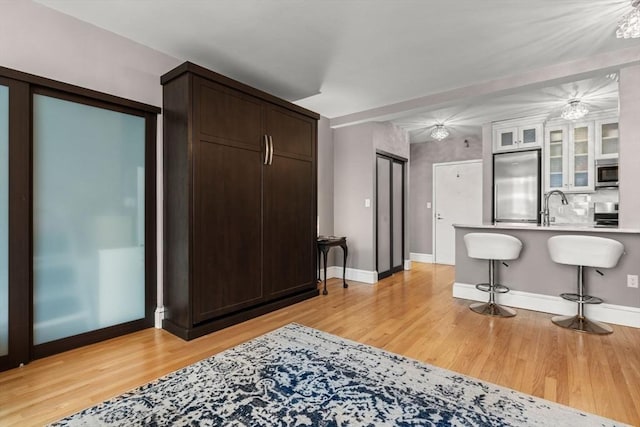 42 8th St Unit 4106, Boston, MA 02129 - kitchen featuring built in fridge, a breakfast bar area, light countertops, light wood finished floors, and glass insert cabinets