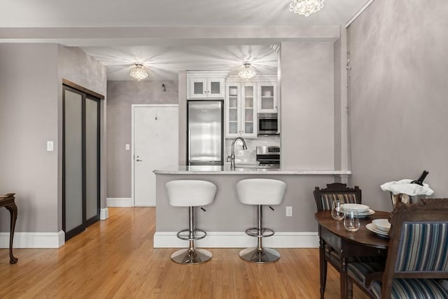 42 8th St Unit 4106, Boston, MA 02129 - kitchen with appliances with stainless steel finishes, white cabinetry, a peninsula, a kitchen bar, and light wood-style flooring