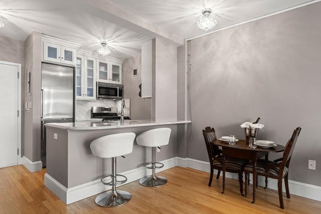 42 8th St Unit 4106, Boston, MA 02129 - kitchen featuring stainless steel appliances, tasteful backsplash, a kitchen bar, light wood-type flooring, and a peninsula
