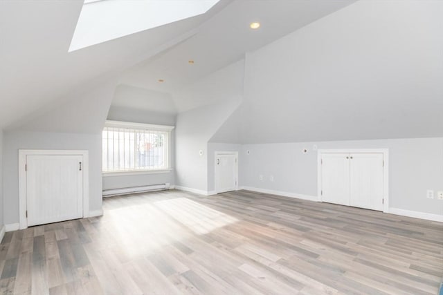 additional living space featuring a baseboard heating unit, vaulted ceiling, light wood finished floors, and baseboards