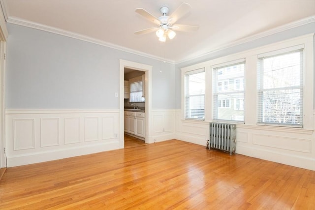 unfurnished room featuring ornamental molding, light wood-type flooring, radiator, and a healthy amount of sunlight