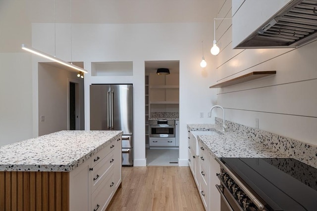 kitchen with extractor fan, stainless steel appliances, white cabinetry, and light hardwood / wood-style flooring