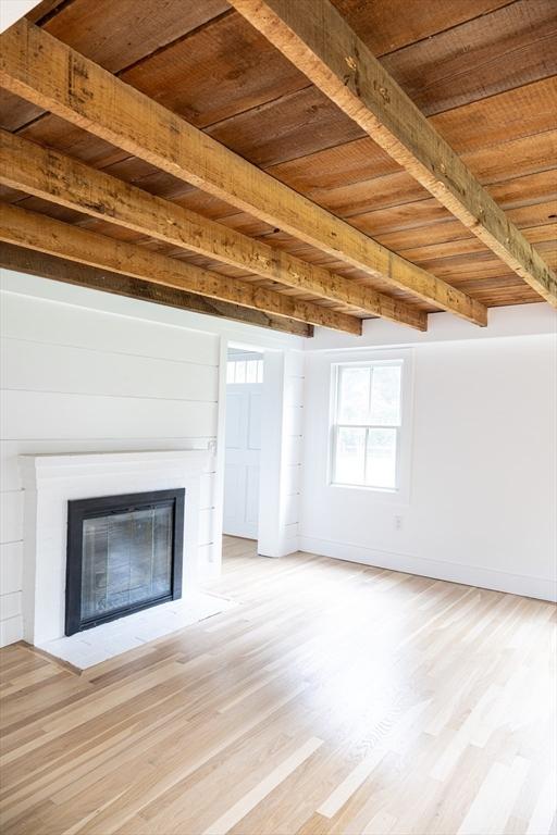 unfurnished living room with beam ceiling, light hardwood / wood-style floors, and wood ceiling