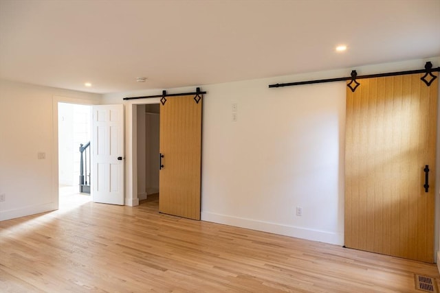 spare room featuring a barn door and light wood-type flooring