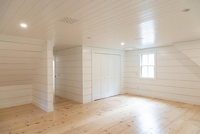 bonus room featuring light hardwood / wood-style floors and wooden walls