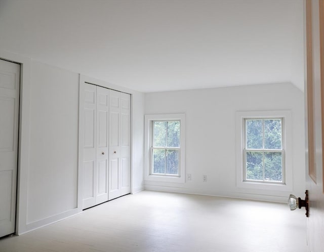 unfurnished bedroom with multiple windows and vaulted ceiling