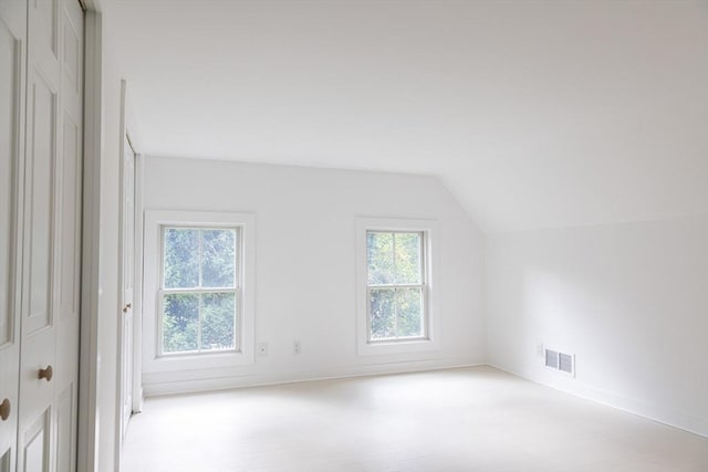 bonus room featuring plenty of natural light, light colored carpet, and vaulted ceiling