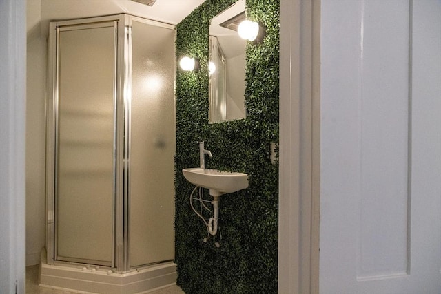 bathroom featuring a shower with door and sink