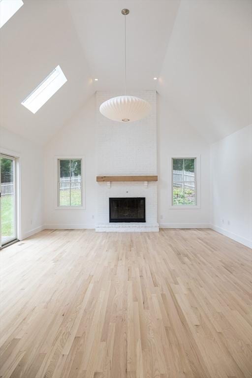 unfurnished living room with plenty of natural light, light hardwood / wood-style floors, and a brick fireplace