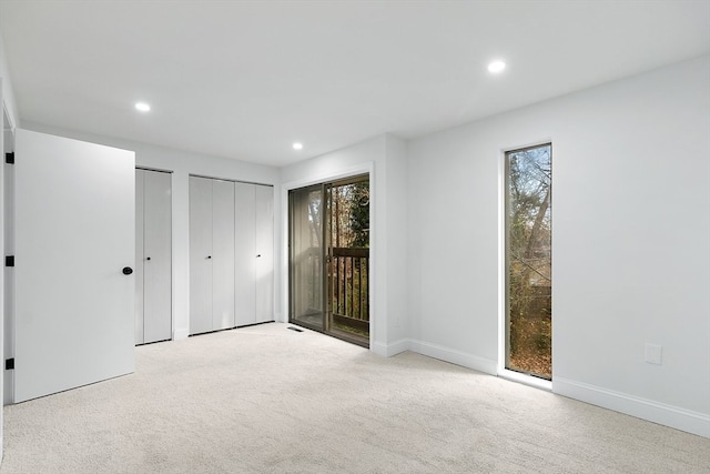 unfurnished bedroom featuring access to exterior, light colored carpet, and multiple windows