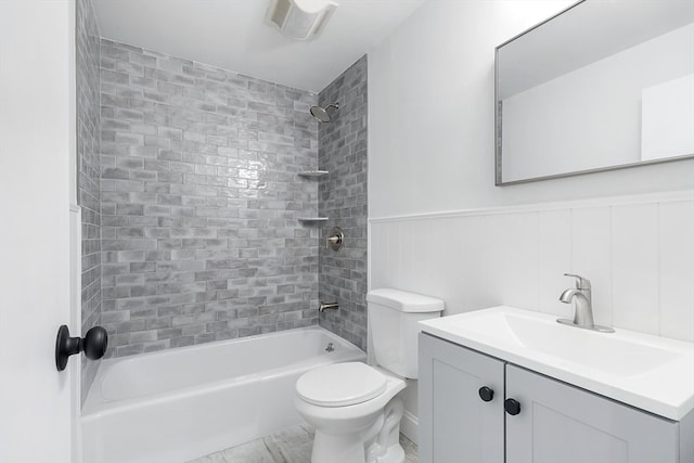 full bathroom featuring vanity, tiled shower / bath, and toilet