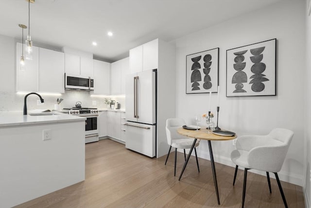 100 Lincoln St Unit 303, Boston, MA 02135 - kitchen featuring white appliances, light wood-style flooring, light countertops, tasteful backsplash, and white cabinets