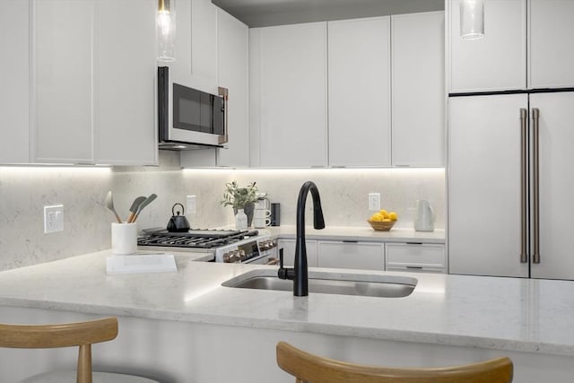 100 Lincoln St Unit 303, Boston, MA 02135 - kitchen with white cabinetry, stainless steel range with gas stovetop, and decorative backsplash