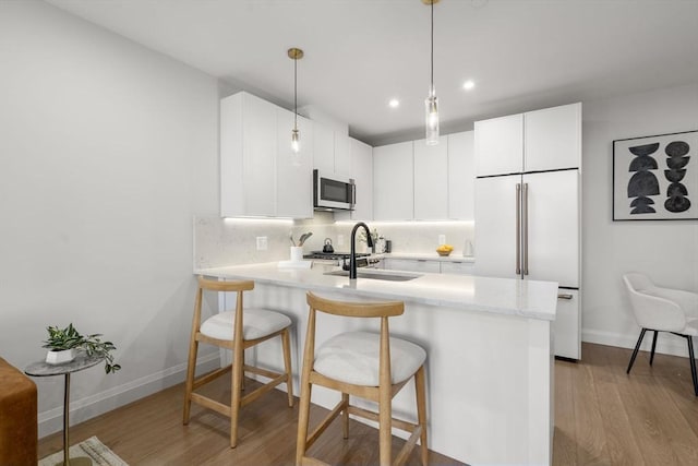 100 Lincoln St Unit 303, Boston, MA 02135 - kitchen with high end refrigerator, wood finished floors, a peninsula, decorative backsplash, and a kitchen breakfast bar