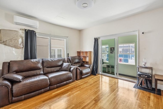 living area with an AC wall unit, plenty of natural light, and wood finished floors
