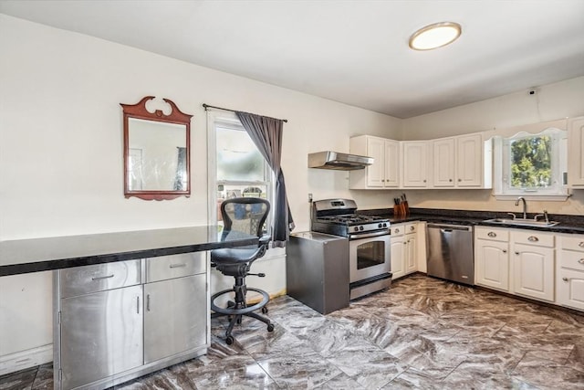 kitchen with dark countertops, appliances with stainless steel finishes, a sink, marble finish floor, and under cabinet range hood