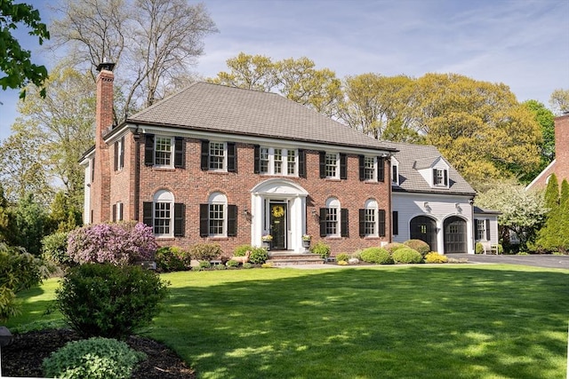 115 Rutledge, Belmont, MA 02478 - georgian-style home featuring a chimney, a front lawn, a garage, and brick siding