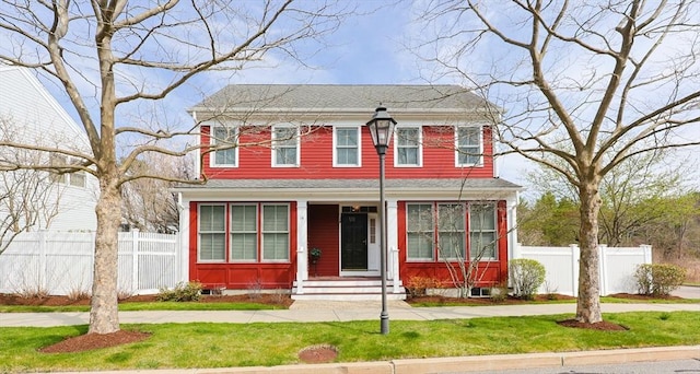 view of front of home with a front lawn, roof with shingles, fence, and entry steps