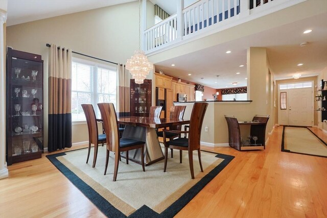 dining room with baseboards, a notable chandelier, light wood-style floors, a high ceiling, and recessed lighting
