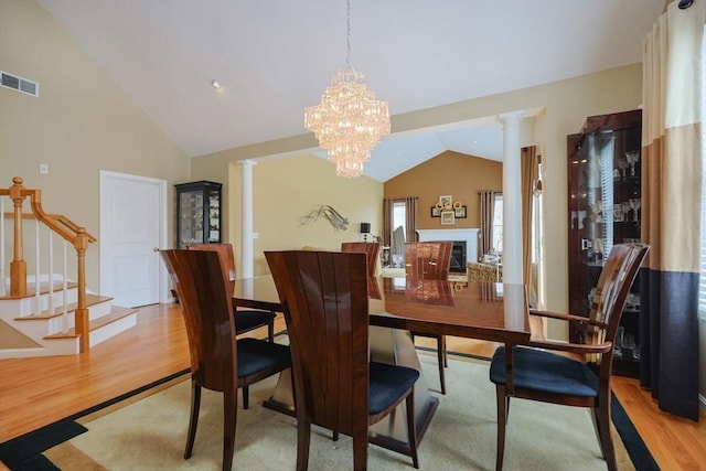 dining room featuring light wood-style floors, decorative columns, lofted ceiling, visible vents, and stairway