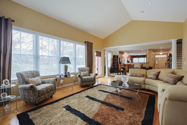 living area featuring ornate columns, high vaulted ceiling, and wood finished floors