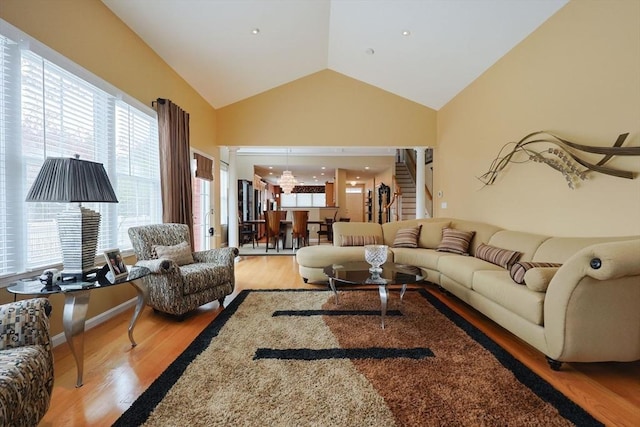 living room featuring high vaulted ceiling, plenty of natural light, stairs, and wood finished floors