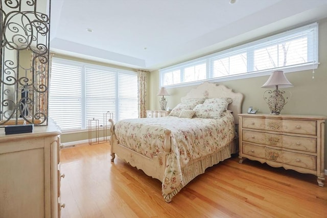bedroom featuring a tray ceiling and light wood-type flooring