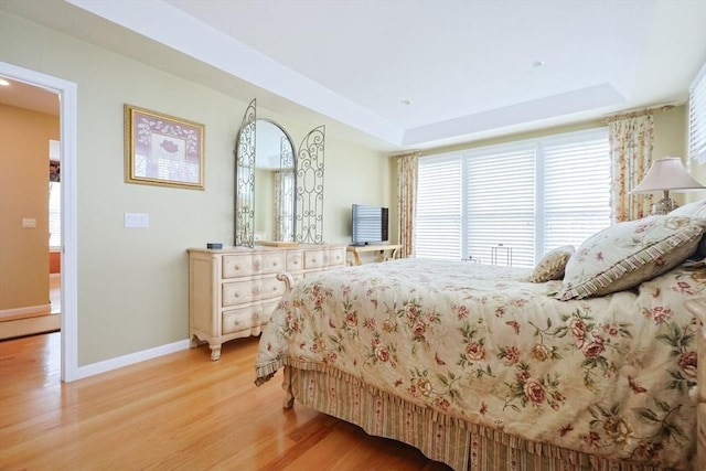 bedroom featuring baseboards, recessed lighting, light wood finished floors, and a tray ceiling