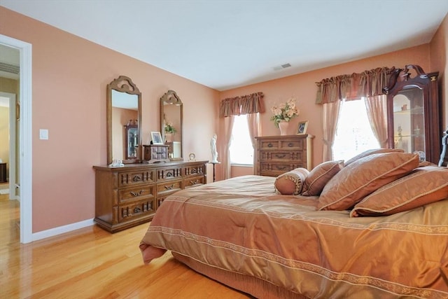 bedroom with visible vents, light wood-style floors, and baseboards