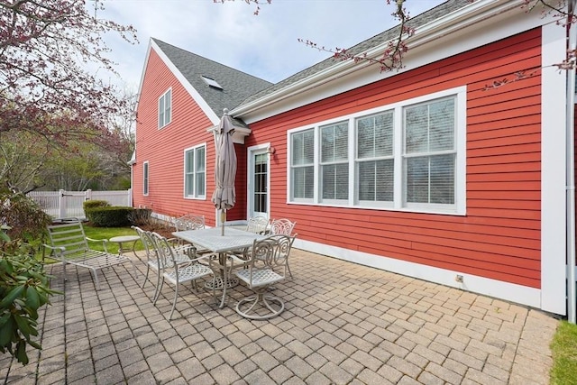 back of property with fence, outdoor dining space, and a patio area