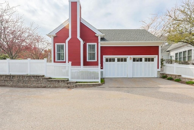 view of front of house with fence private yard, a garage, roof with shingles, a chimney, and concrete driveway