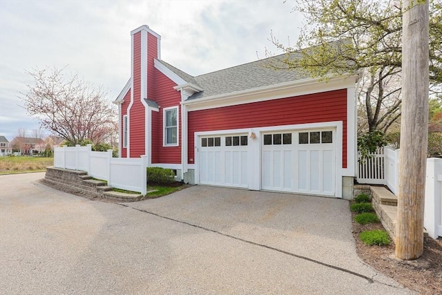 garage with fence and concrete driveway