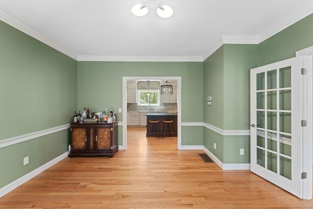 dining space with light wood-type flooring, ornamental molding, baseboards, and a chandelier