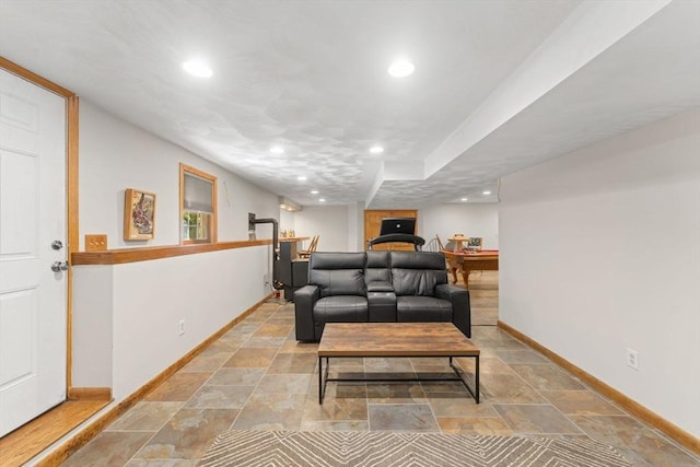 living area featuring baseboards, light stone finish flooring, and recessed lighting