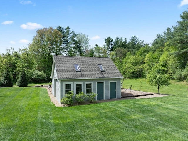rear view of house featuring a lawn, a shingled roof, and an outbuilding