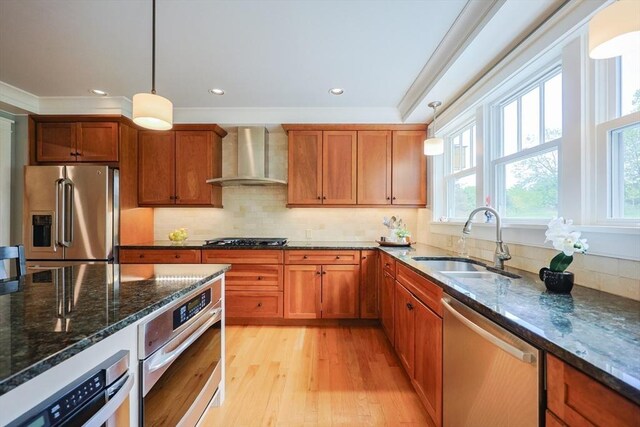185 Read St, Seekonk, MA 02771 - kitchen featuring appliances with stainless steel finishes, wall chimney range hood, a sink, light wood finished floors, and pendant lighting