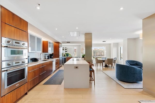 kitchen featuring modern cabinets, stainless steel appliances, a center island, a breakfast bar area, and light countertops