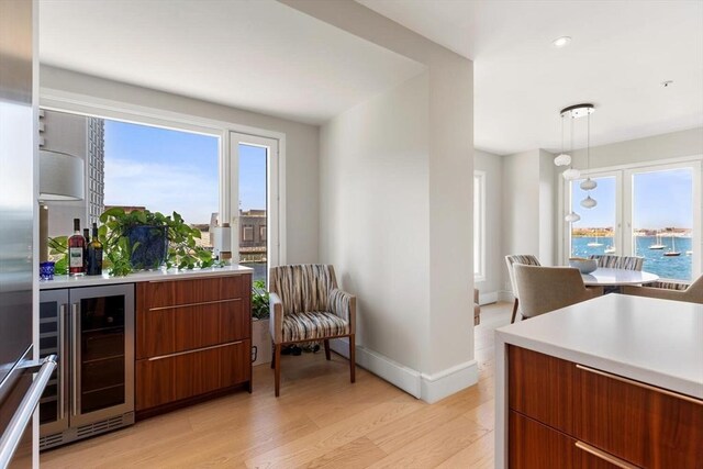 kitchen with beverage cooler, modern cabinets, light wood-style flooring, light countertops, and recessed lighting