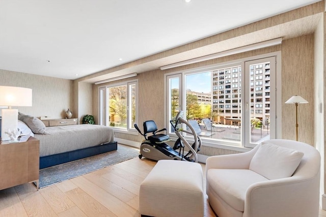bedroom featuring wood finished floors, wallpapered walls, and access to outside