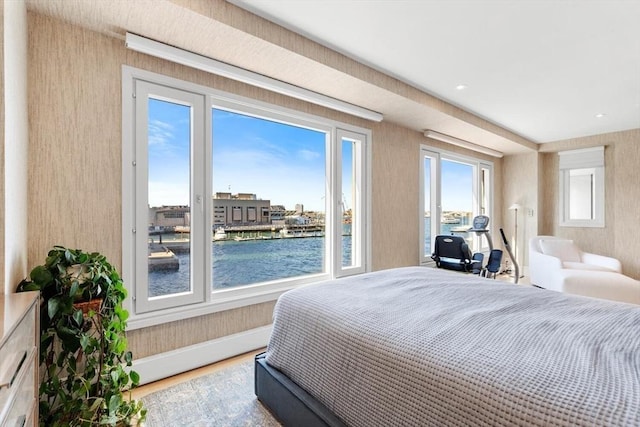 bedroom featuring a water view, wood finished floors, and baseboards