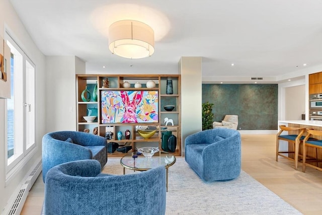 living area featuring a baseboard heating unit, recessed lighting, and light wood finished floors