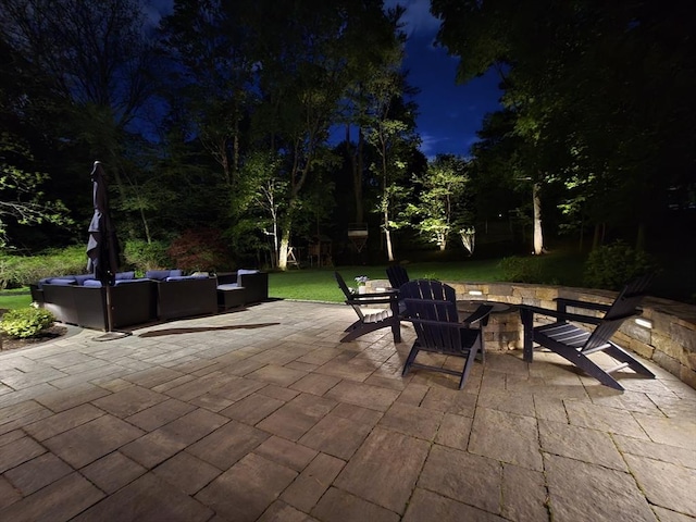 patio at night featuring an outdoor living space with a fire pit and a yard