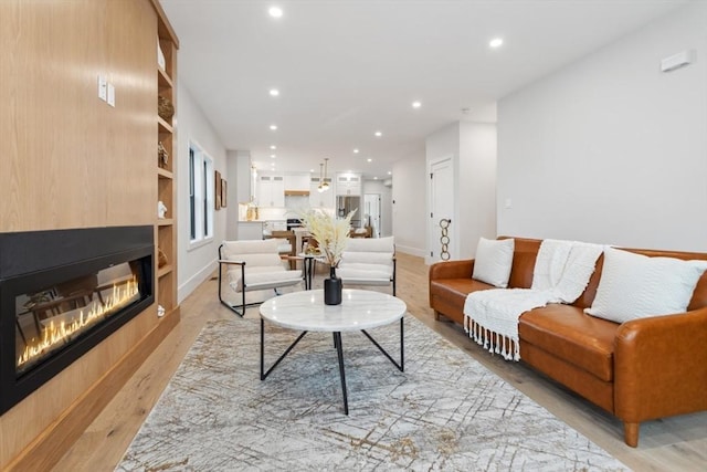 living room with built in shelves and light hardwood / wood-style floors