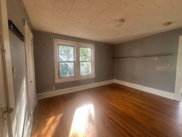 spare room featuring wood finished floors and baseboards