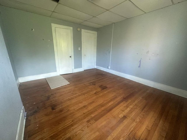 unfurnished room featuring a paneled ceiling, wood finished floors, and baseboards