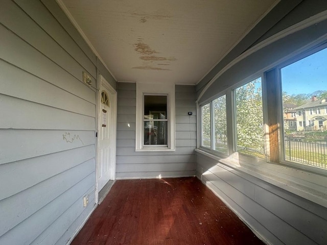 unfurnished sunroom featuring wood finished floors and wood walls